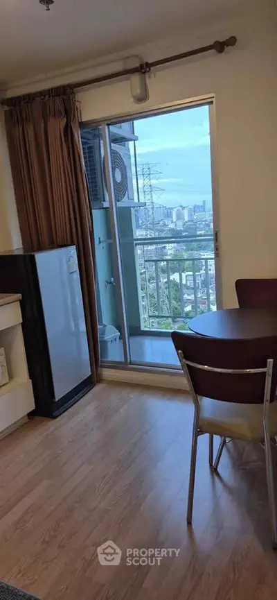 Cozy apartment with balcony view, featuring wooden flooring and compact dining area.