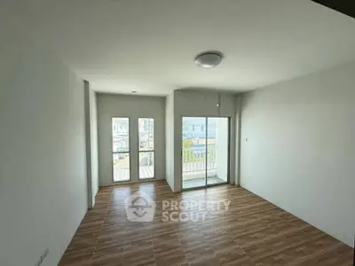 Spacious empty room with large windows and wooden flooring, ideal for customization.