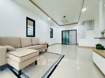 Spacious modern living room with elegant beige sofa and sleek tile flooring.