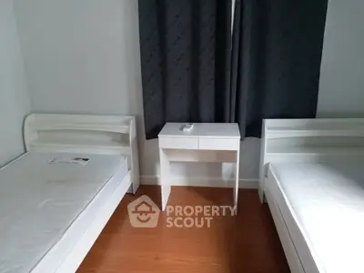 Minimalist bedroom with twin beds and a small desk, perfect for a cozy living space.