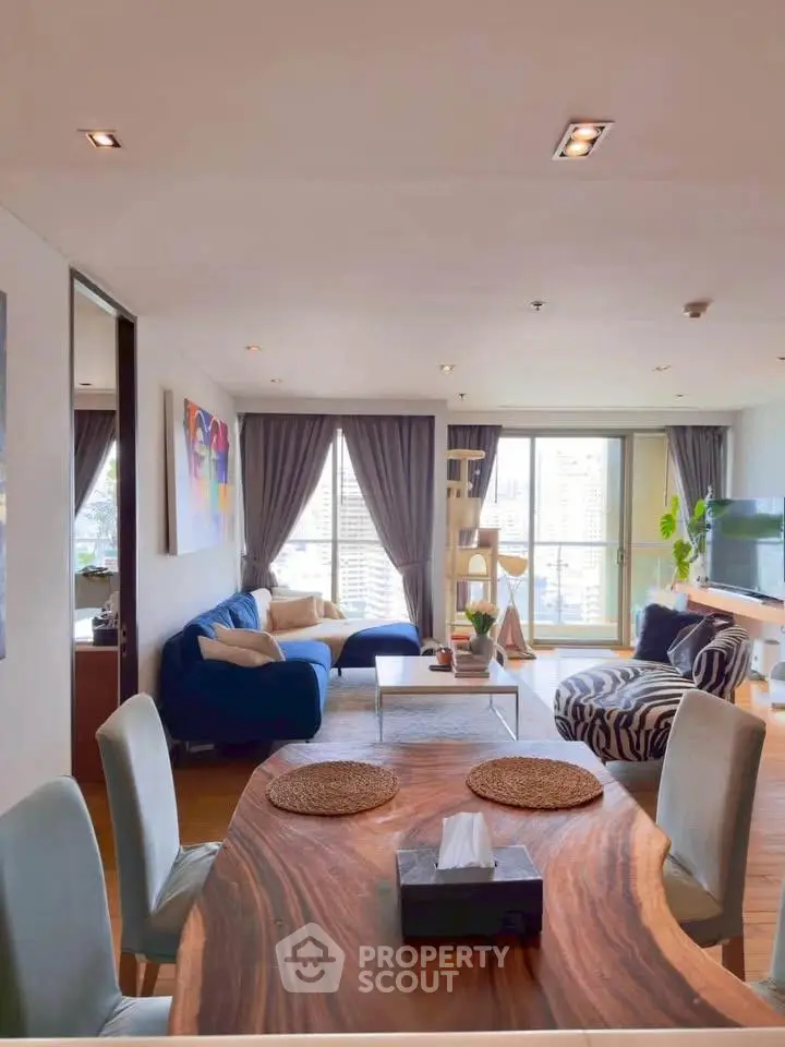 Spacious living room with modern decor and city view, featuring stylish furniture and natural light.