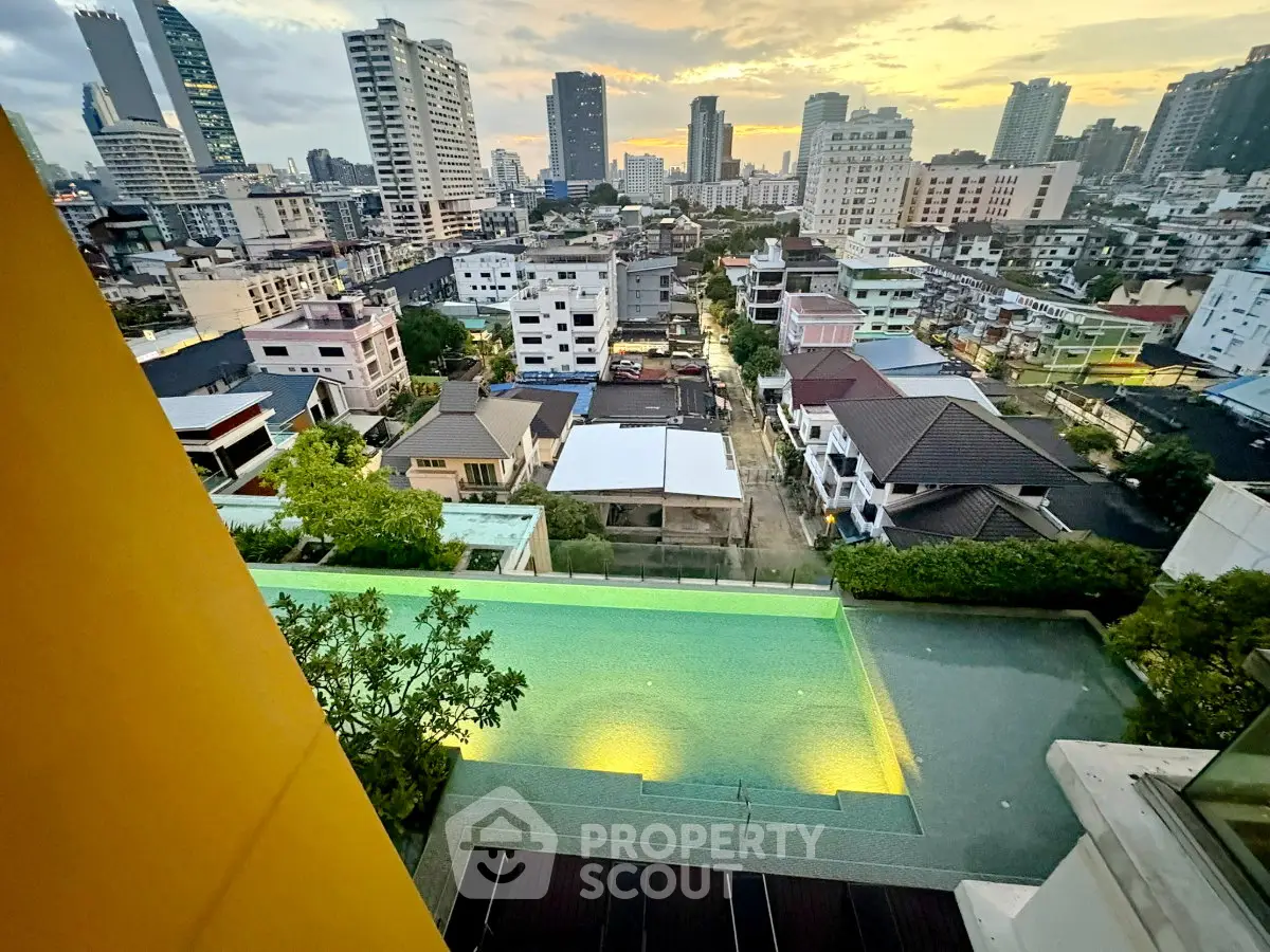 Stunning cityscape view from a high-rise building with a luxurious rooftop pool at sunset.