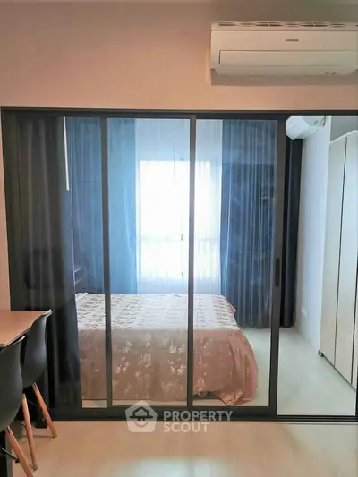 Modern bedroom with glass sliding doors and air conditioning, featuring elegant decor and natural light.