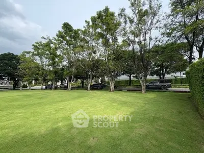 Expansive green lawn with trees, perfect for outdoor activities and relaxation.