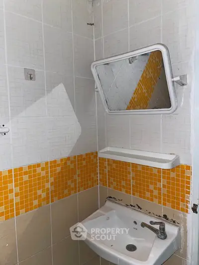 Compact bathroom corner with orange mosaic tiles and wall-mounted sink.