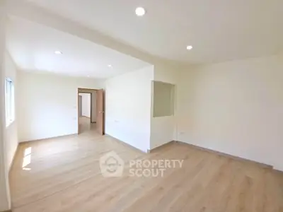 Spacious empty room with wooden flooring and bright natural light, ideal for customization.