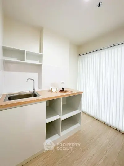 Modern minimalist kitchen with sleek wooden countertops and ample storage space.
