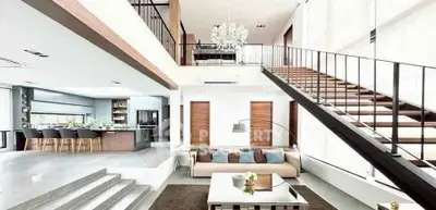 Luxurious modern living room with high ceilings, elegant staircase, and open kitchen layout.