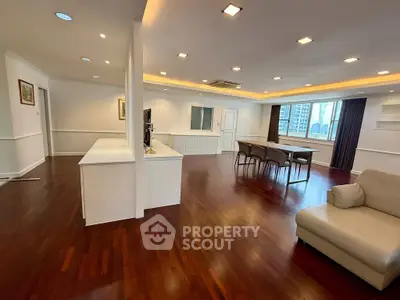 Spacious open-plan living room with hardwood floors and modern furnishings in a high-rise apartment.