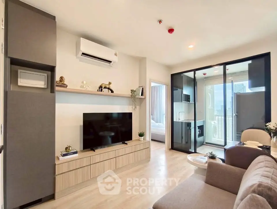 Modern living room with sleek design, large TV, and glass doors leading to a balcony with city view.