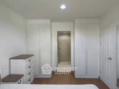 Spacious bedroom with built-in wardrobes and elegant white furniture, perfect for modern living.