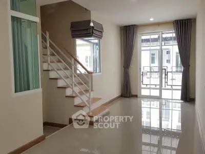 Spacious modern living room with staircase and large windows for natural light.