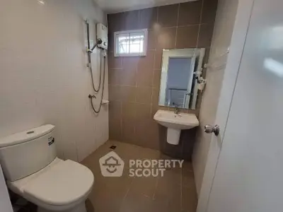 Modern bathroom with sleek fixtures and neutral tiles, featuring a shower and toilet.