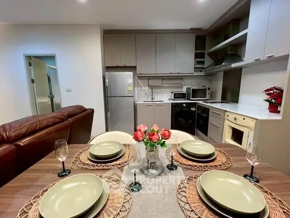 Modern kitchen with dining area, featuring sleek appliances and elegant table setting.