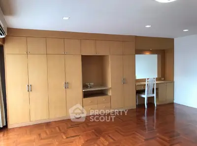 Spacious bedroom with built-in wooden wardrobe and elegant parquet flooring