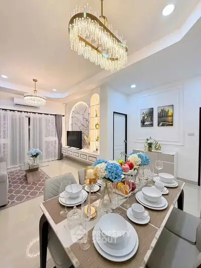 Luxurious open-plan living and dining area with elegant chandeliers and modern decor.