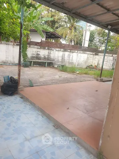 Spacious outdoor patio with tiled flooring and lush greenery, perfect for relaxation and entertainment.