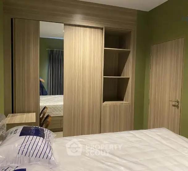 Modern bedroom with built-in wooden wardrobe and green accent wall.