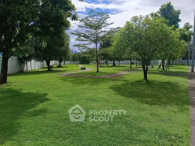 Spacious green garden area with trees and walking paths in a serene residential community.