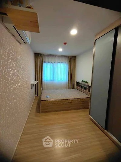 Cozy bedroom with modern design, featuring wooden flooring and ample natural light.