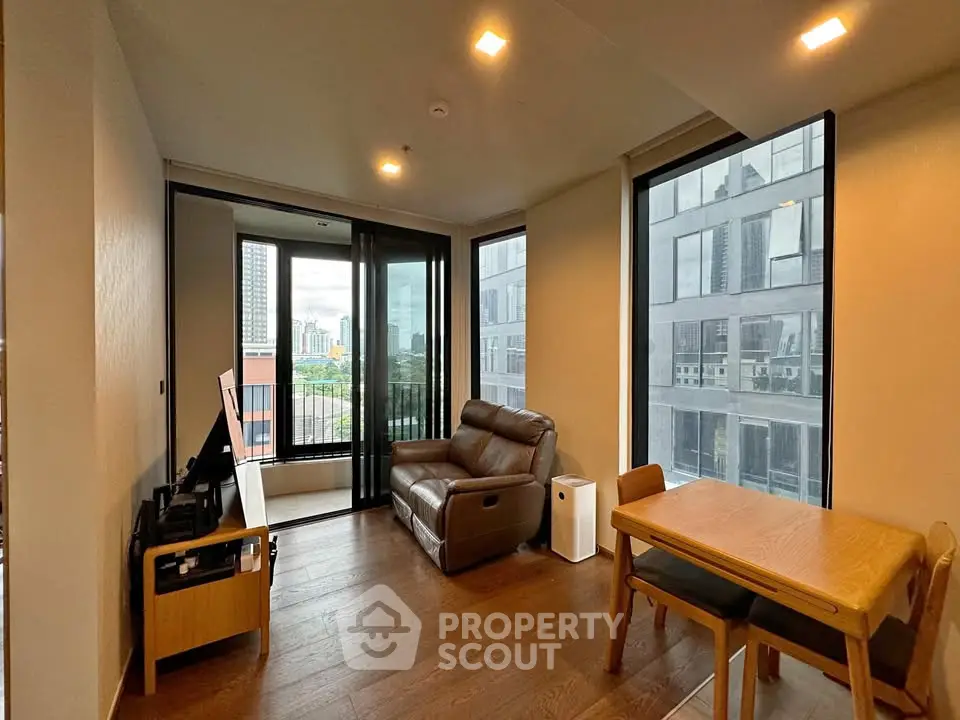 Modern living room with city view, featuring cozy seating and dining area in a high-rise apartment.