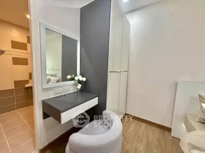Modern bedroom with stylish vanity and cozy chair, featuring sleek design and elegant decor.