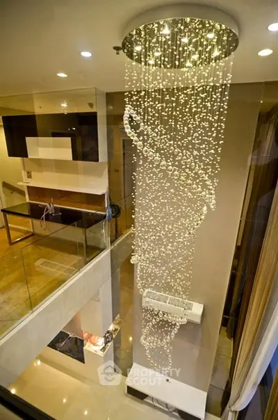 Luxurious modern interior with stunning spiral chandelier and glass balcony overlooking elegant living space.