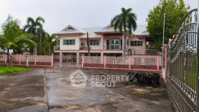 Spacious two-story house with gated entrance and lush palm trees, perfect for family living.