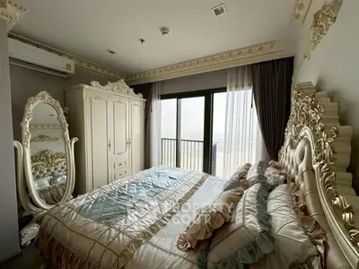 Luxurious bedroom with ornate furniture and stunning city view from balcony.