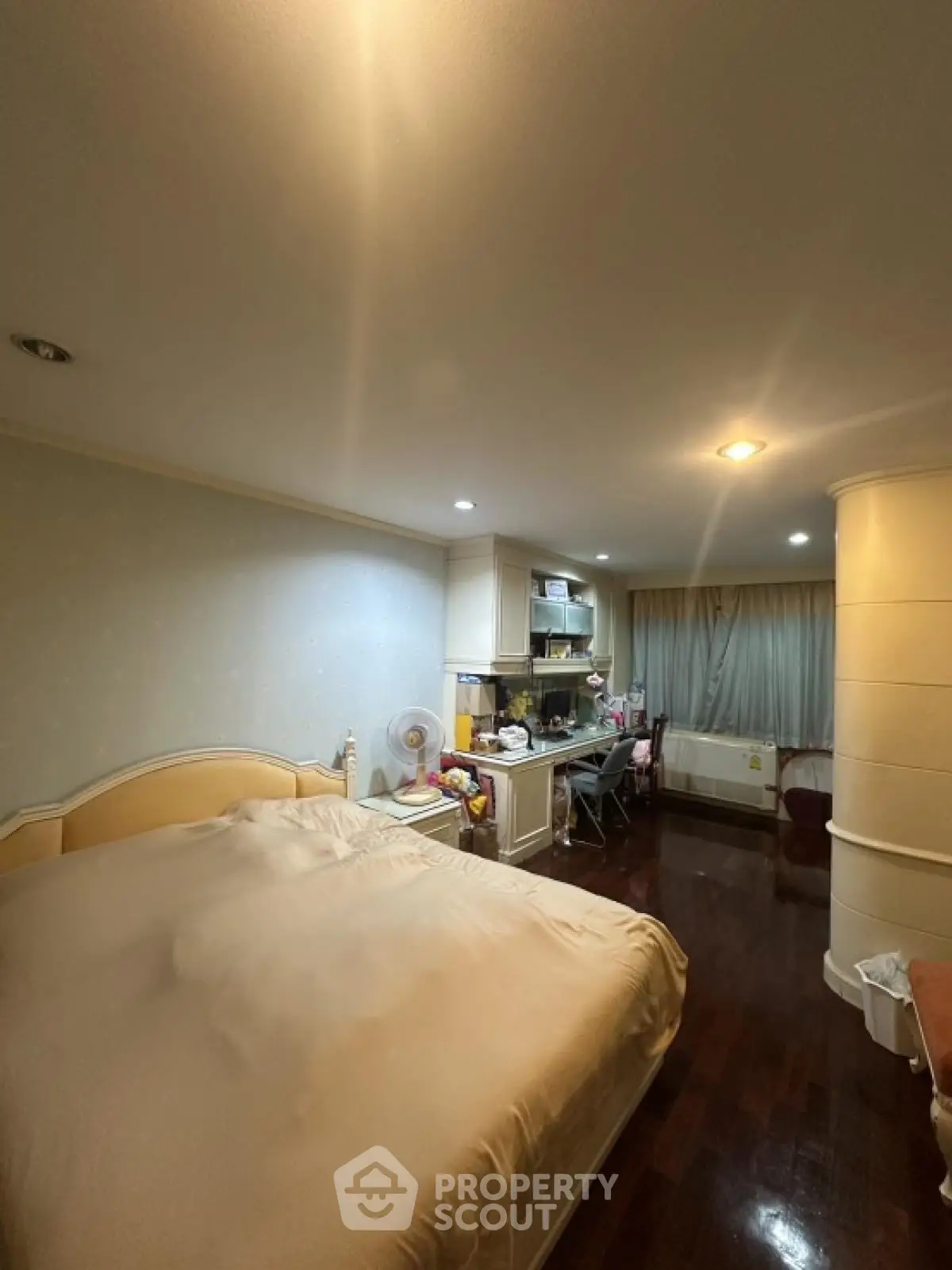 Cozy bedroom with integrated kitchen area, featuring warm lighting and wooden flooring.