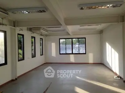 Spacious empty room with large windows and natural light, ideal for office or studio space.