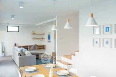 Modern open-plan living room with stylish decor and dining area, featuring contemporary lighting and neutral tones.