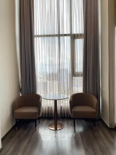 Elegant seating area with tall windows and modern chairs in a stylish apartment.