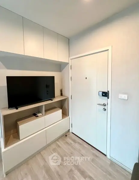 Modern apartment entrance with sleek TV unit and storage cabinets