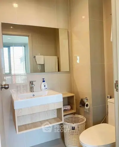 Modern bathroom with sleek sink and mirror, featuring neutral tones and contemporary design.