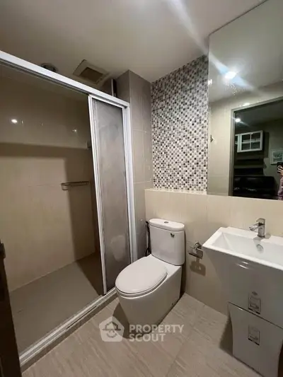 Modern bathroom with sleek shower and stylish vanity in contemporary apartment.