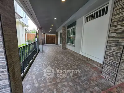 Spacious covered balcony with elegant tile flooring and modern railing in a luxury home.
