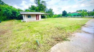 Spacious plot with small house and lush greenery, ideal for development.