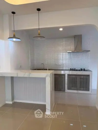 Modern kitchen with sleek design, featuring a gas stove and stylish lighting, perfect for culinary enthusiasts.