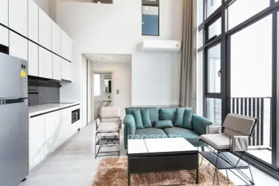 Modern living room with high ceilings and large windows in a stylish apartment.