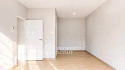 Spacious empty room with wooden flooring and white walls, ready for customization.