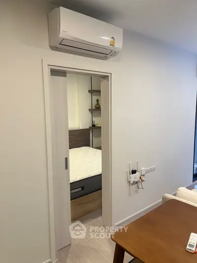Modern interior with sliding door leading to a cozy bedroom, featuring a wall-mounted air conditioner.
