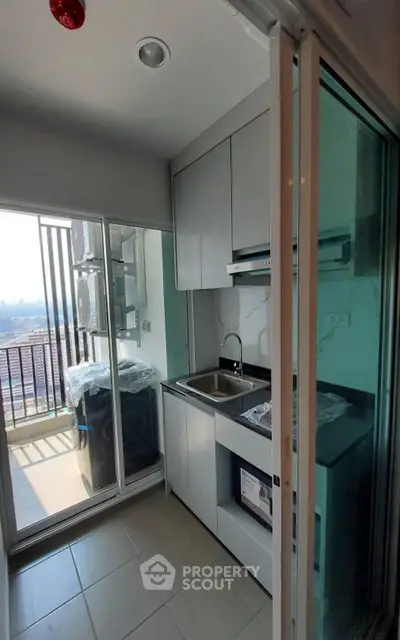 Modern compact kitchen with balcony view in high-rise apartment