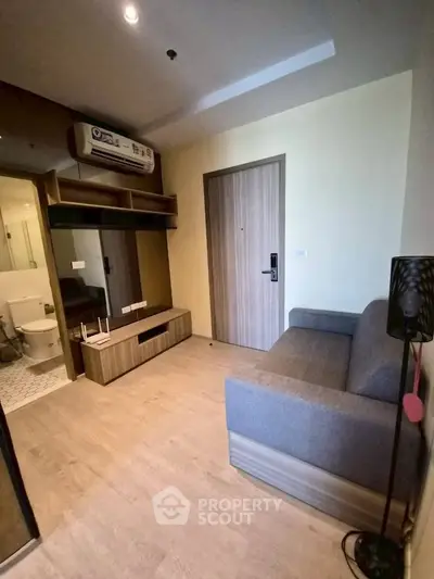 Modern living room with cozy sofa and wooden accents near bathroom entrance.