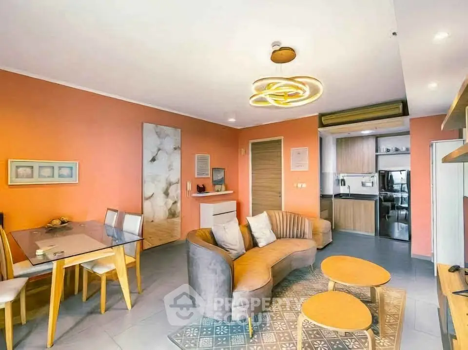 Stylish modern living room with open kitchen and unique lighting fixtures.