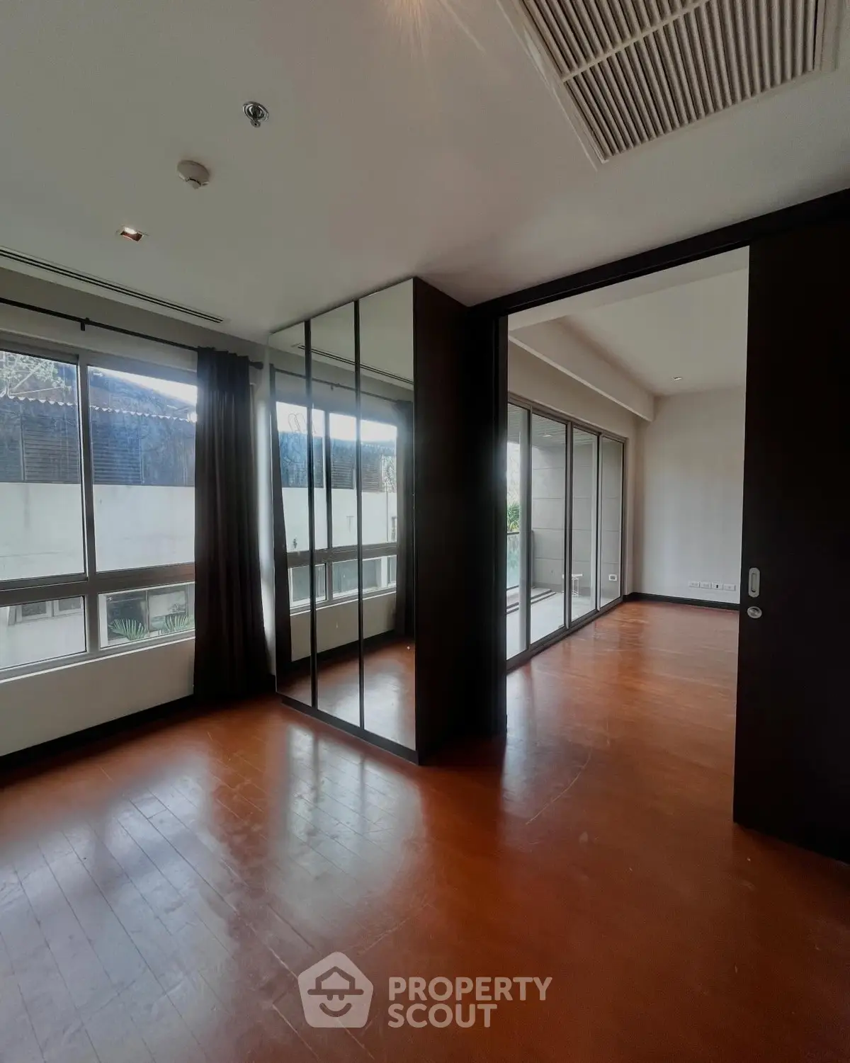 Spacious modern living room with floor-to-ceiling windows and wooden flooring
