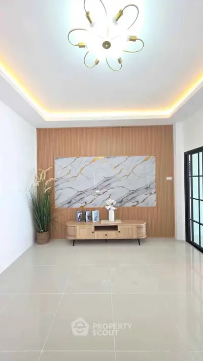 Modern living room with elegant lighting and stylish decor, featuring a marble accent wall and sleek furniture.