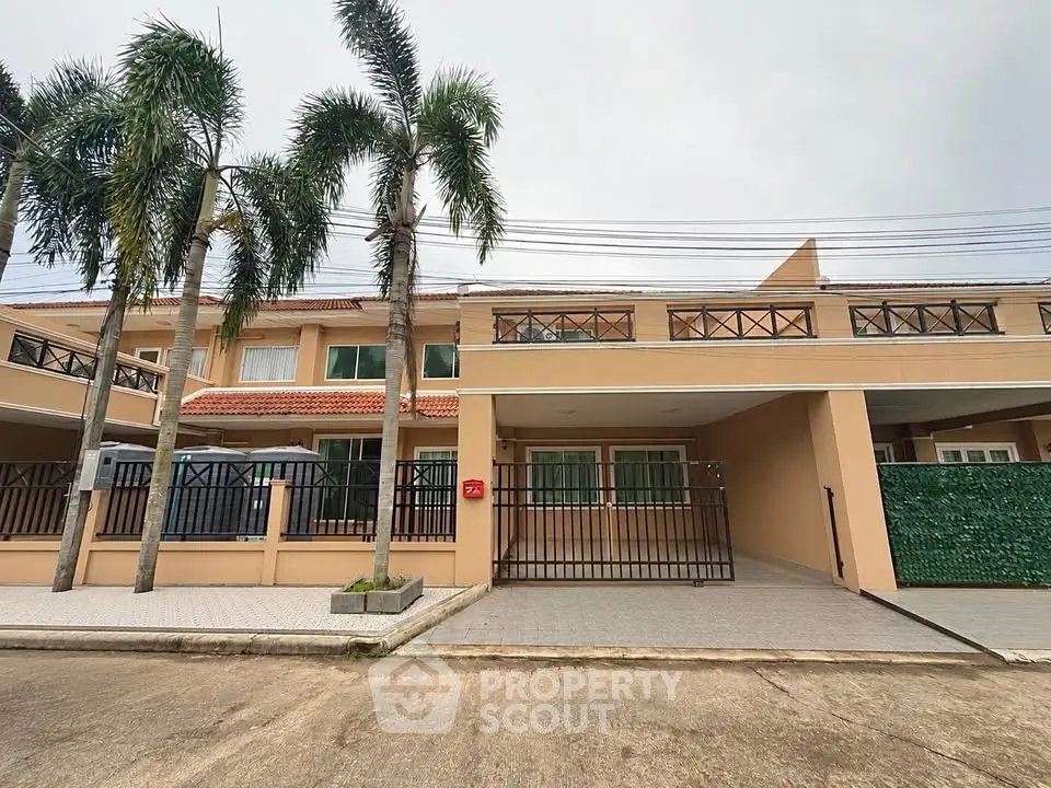 Spacious two-story house with modern design and gated driveway in a tropical setting.