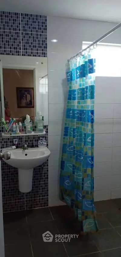 Modern bathroom with stylish blue shower curtain and sleek sink design.