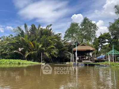 Scenic riverside property with lush greenery and traditional wooden gazebo.